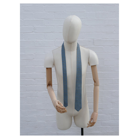 Lovewell Khaki silk tie designed by Niki Fulton. A teal & khaki print. Seen here on a mannequin.